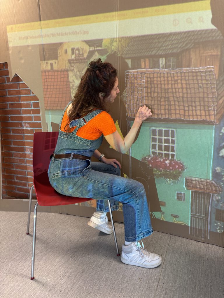 Persona participando en un proceso de creación escenográfica, pintando una casa sobre un soporte artístico.
La imagen refleja el trabajo creativo como herramienta de expresión y construcción colectiva dentro de procesos artísticos comunitarios.