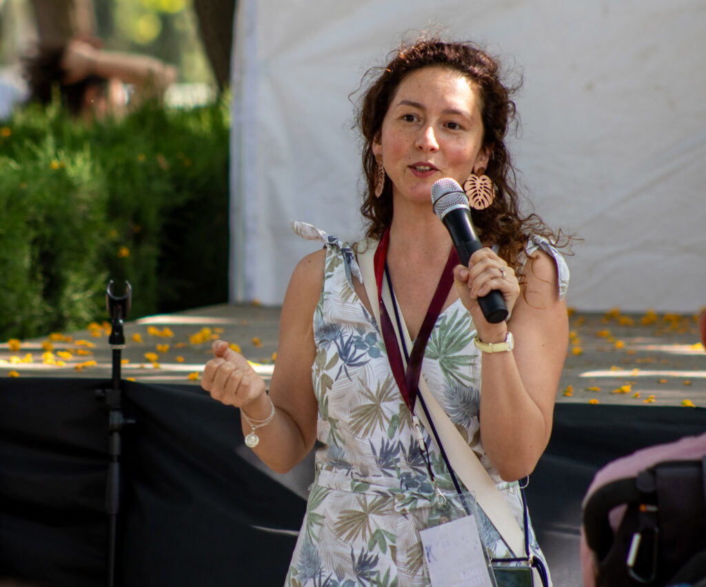 Persona hablando con micrófono en un espacio al aire libre, dirigiéndose a un grupo durante una actividad.
La imagen refleja la facilitación de espacios de diálogo, participación y expresión en contextos comunitarios.